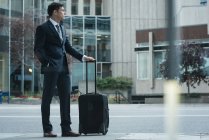 Businessman with suitcase on street standing outside the building — Stock Photo