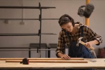 Junge Kunsthandwerkerin arbeitet in Werkstatt mit Hammer. — Stockfoto