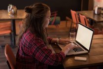 Женщина работает с ноутбуком за столом в кафе — стоковое фото