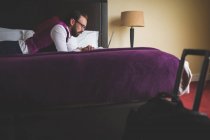 Бизнесмен с помощью ноутбука на кровати в отеле — стоковое фото