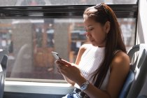 Teenage girl using mobile phone in the bus — Stock Photo