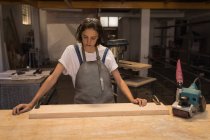 Junge Kunsthandwerkerin arbeitet in Werkstatt mit Holz. — Stockfoto