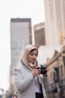 Jeune femme en hijab regardant des photos — Photo de stock