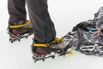 Baixa seção de alpinista com crampons em pé na neve durante o inverno — Fotografia de Stock