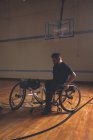 Jeune homme handicapé en fauteuil roulant au terrain de basketball — Photo de stock