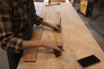 Sezione media dell'artigiana che misura il pezzo di legno in officina . — Foto stock