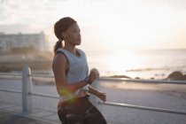 Jovem mulher correndo perto da praia durante o pôr do sol — Fotografia de Stock