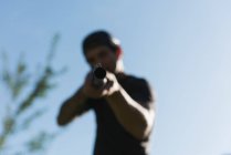 Homem atirando com arma em um dia ensolarado — Fotografia de Stock