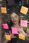 Female executive looking sticky notes in office — Stock Photo