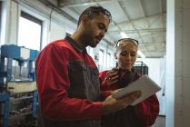 Два работника обсуждают за цифровым планшетом на заводе — стоковое фото