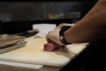 Chef tenant rouleau de viande de poisson sur une planche à découper — Photo de stock
