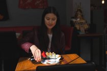 Jeune femme ayant de la nourriture sushi au restaurant — Photo de stock
