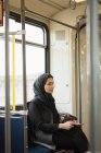 Mulher no hijab usando tablet digital enquanto viaja no trem — Fotografia de Stock