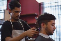 Hombre consiguiendo su pelo recortado con trimmer en la barbería - foto de stock