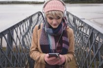 Жінка слухає музику на мобільному телефоні в мосту — стокове фото