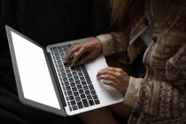 Seção média de mulher usando laptop dentro de casa . — Fotografia de Stock