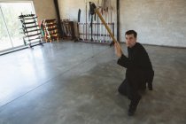 Kung fu fighter practicing with long pole in fitness studio. — Stock Photo