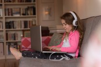 Menina usando laptop no sofá na sala de estar em casa — Fotografia de Stock
