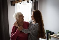 Großmutter und Enkelin umarmen sich im heimischen Wohnzimmer — Stockfoto