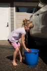 Mädchen wäscht an einem sonnigen Tag ein Auto in der Garage — Stockfoto