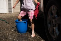 Baixa seção de menina colocando a perna no balde enquanto lava o carro — Fotografia de Stock