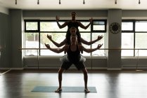 Groupe de personnes en forme pratiquant l'acroyoga dans un studio de fitness . — Photo de stock