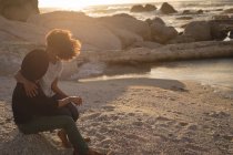 Coppia romantica che si guarda mentre si siede sulla spiaggia durante il tramonto — Foto stock