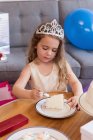 Jolie fille ayant tranche de gâteau dans le salon à la maison — Photo de stock