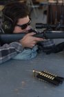 Nahaufnahme eines Mannes, der mit einem Scharfschützengewehr auf eine Zielscheibe im Schießstand schießt — Stockfoto