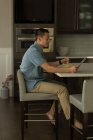 Mann benutzt digitales Tablet beim Frühstück zu Hause — Stockfoto