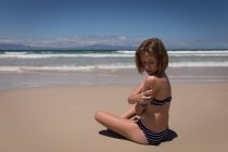 Ragazza adolescente che applica crema solare lozione sul retro in spiaggia — Foto stock