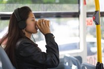 Side view of teenage girl having coffee in the bus — Stock Photo