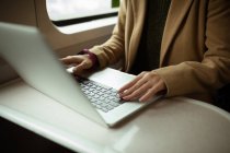 Primo piano di capelli rossi giovane donna utilizzando il suo computer portatile in treno — Foto stock