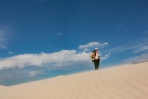Wanderin mit Rucksack steht an einem sonnigen Tag auf Sand — Stockfoto