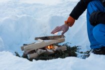 Nahaufnahme männlicher Hand beim Aufwärmen am Lagerfeuer im Schnee. — Stockfoto