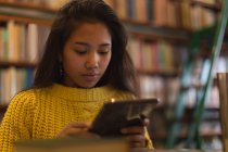 Дівчина-підліток використовує цифровий планшет у бібліотеці — стокове фото