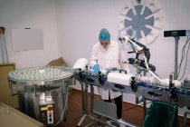 Trabajadora monitoreando los frascos de vidrio en la línea de producción en la fábrica - foto de stock