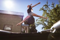 Menina pré-adolescente pulando no trampolim no jardim . — Fotografia de Stock