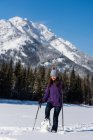 Frau wandert im Winter mit Skistöcken in verschneiter Landschaft. — Stockfoto