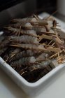Threaded prawns pushed onto skewers kept in a tray — Stock Photo