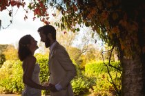 Счастливая невеста и жених смеются в саду — стоковое фото