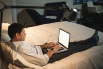 Businessman using laptop in bedroom at hotel — Stock Photo