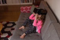 Дівчина використовує гарнітуру віртуальної реальності на дивані у вітальні вдома — стокове фото