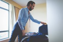 Smart businessman selecting blazer in hotel room — Stock Photo