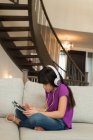 Femme avec écouteurs utilisant une tablette numérique à la maison — Photo de stock