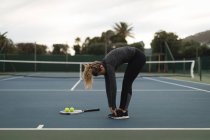 Young woman exercising in tennis court — Stock Photo