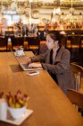 Executivo feminino usando laptop à mesa no hotel — Fotografia de Stock