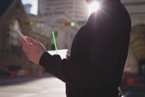 Frau benutzt Handy beim Trinken auf der Straße — Stockfoto