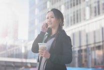 Woman taking on mobile phone while having drink — Stock Photo