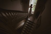 Vista posteriore della sposa in piedi alla finestra a casa — Foto stock